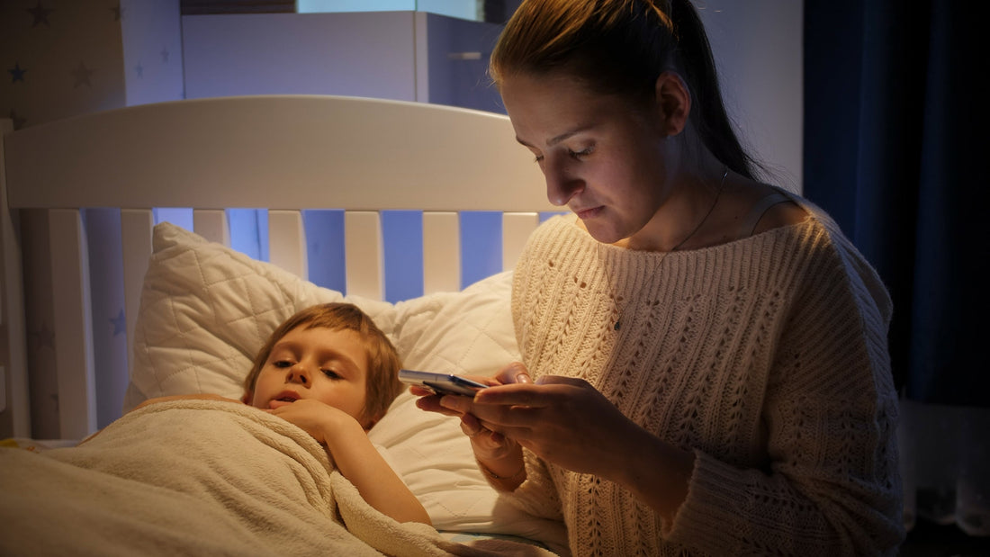 A mom checks her phone while taking care of a sick child. What is the best thing to do when your child suddenly vomits in the middle of the night? Learn more in our complete guide.